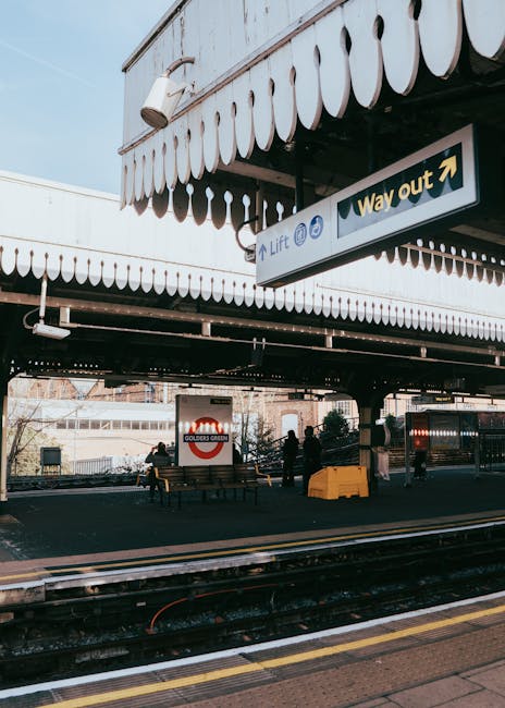 Two movers from Man with Van Barnsbury are preparing a house relocation outside a shop named Guangh, which features a grey facade with gold Chinese characters and the word 'GUANGH' in large metal lett